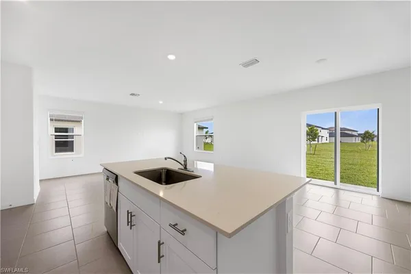 a kitchen with granite countertop a sink a stove top oven and cabinets