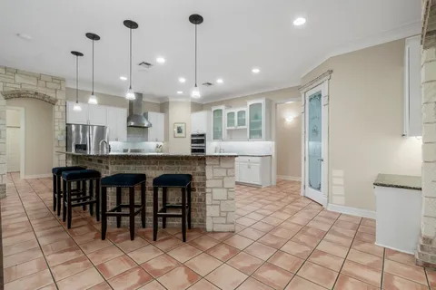 a open kitchen with kitchen island granite countertop a table and chairs in it