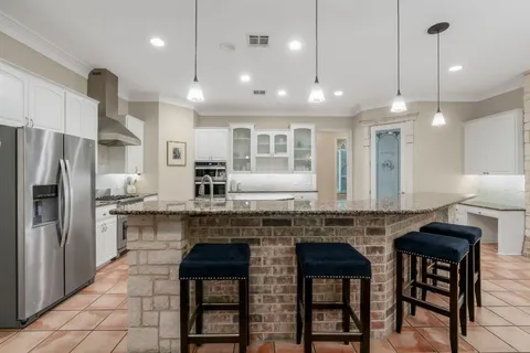 a kitchen with stainless steel appliances granite countertop a stove a refrigerator a kitchen island a sink and a refrigerator