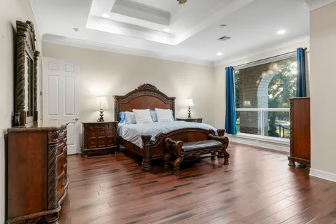a bedroom with a bed a large window with wooden floor