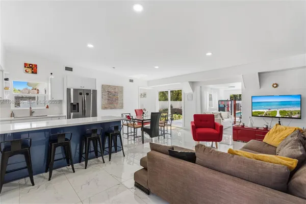 a living room with furniture kitchen view and a large window