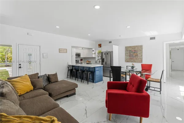 a living room with furniture and a view of kitchen