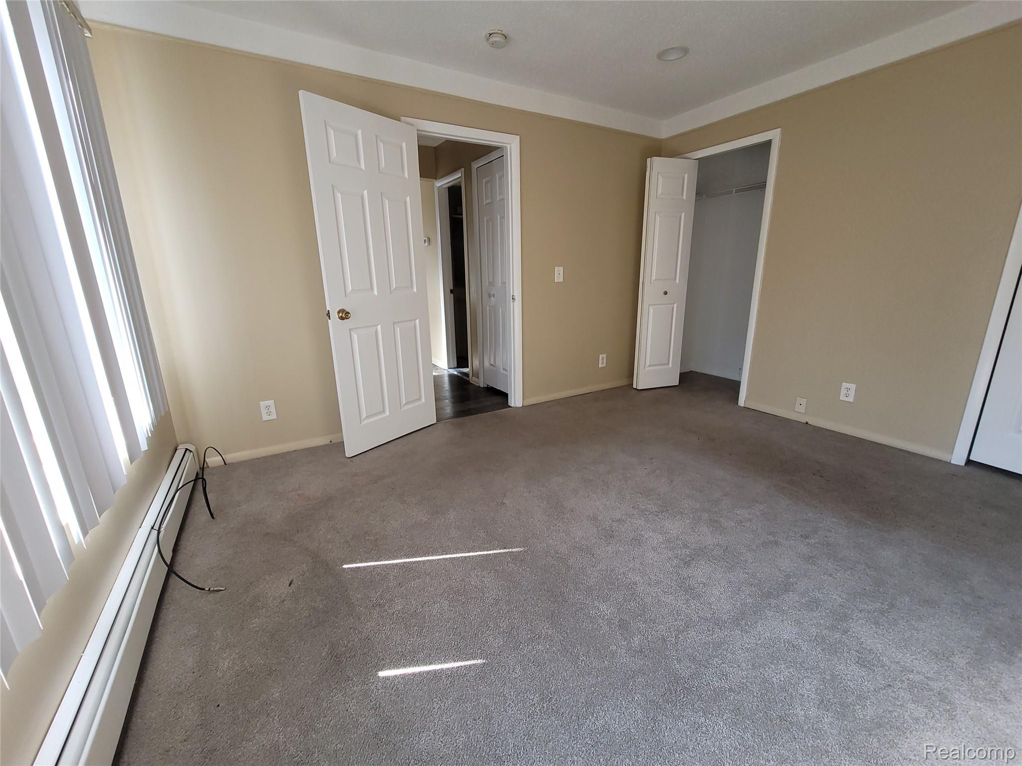 16470 East 9 Mile Road, Unit 104 Eastpointe, MI 48021 - Photo 10 of 14 Unfurnished bedroom featuring baseboard heating, carpet flooring, and a closet