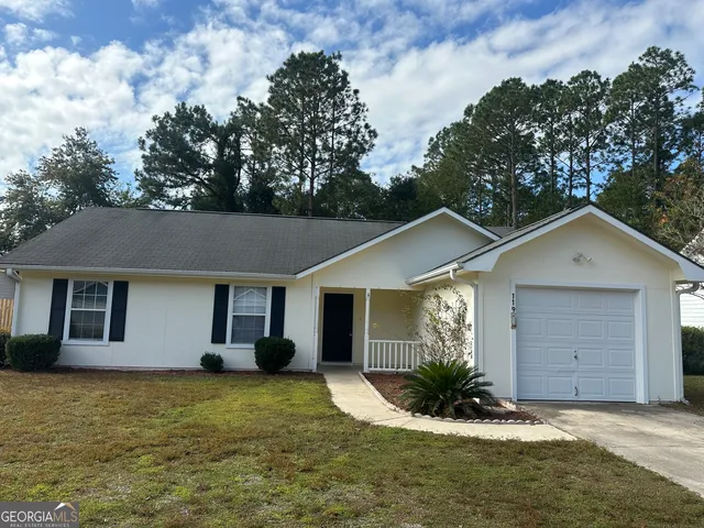 a front view of house with yard and trees in the background