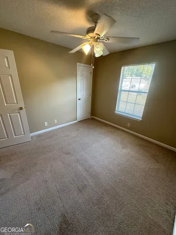 an empty room with a chandelier fan and windows