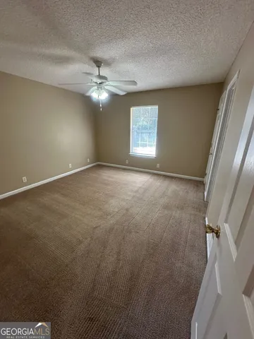 an empty room with windows and fan