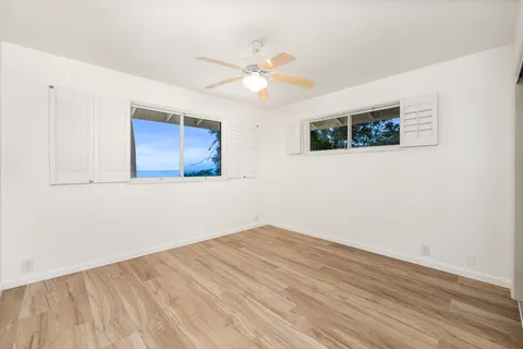 a view of an empty room with window and wooden floor