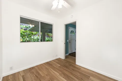 an empty room with wooden floor cabinet and windows