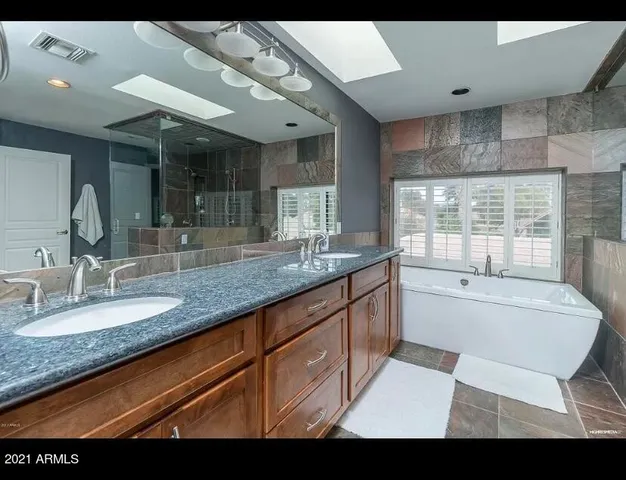 a bathroom with a granite countertop sink a large mirror and shower