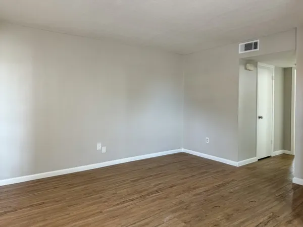 a view of an empty room with wooden floor