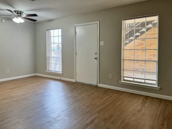 a view of an empty room with wooden floor and a window
