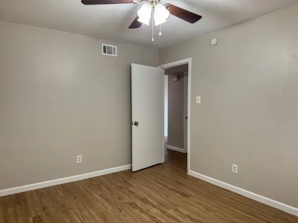an empty room with wooden floor chandelier fan and closet area