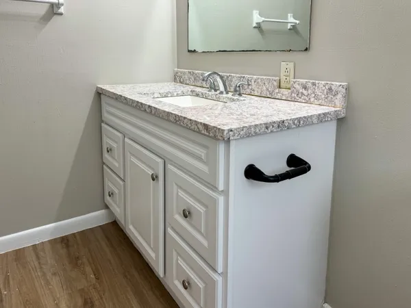 a bathroom with a granite countertop sink a mirror and vanity