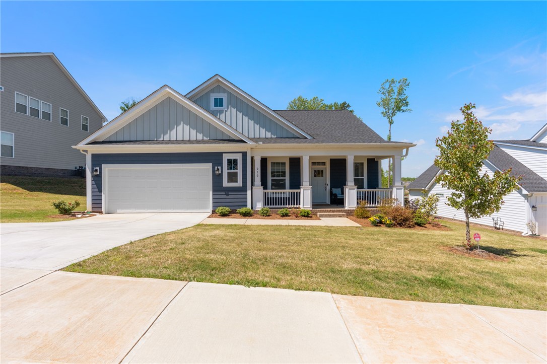 This charming home features a welcoming porch, a convenient garage, and a neatly manicured lawn.