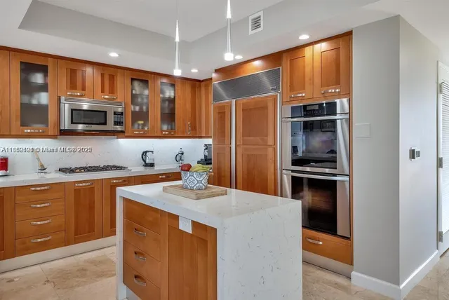 a kitchen with stainless steel appliances kitchen island granite countertop a refrigerator stove and sink