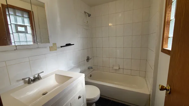 a bathroom with a bathtub shower sink vanity and toilet