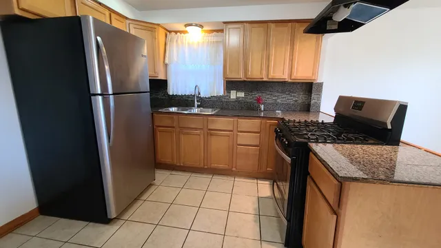 a kitchen with stainless steel appliances granite countertop a refrigerator a stove and a sink
