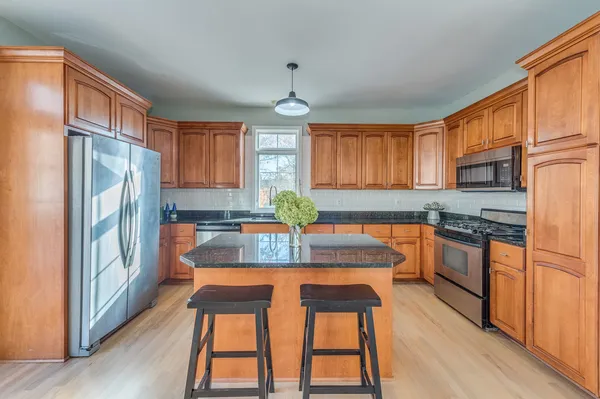 a kitchen with stainless steel appliances granite countertop a refrigerator a sink dishwasher a stove with wooden cabinets and floor