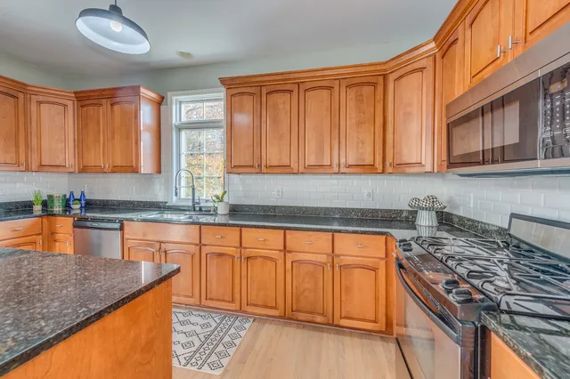 a kitchen with stainless steel appliances granite countertop wooden cabinets and a stove top oven