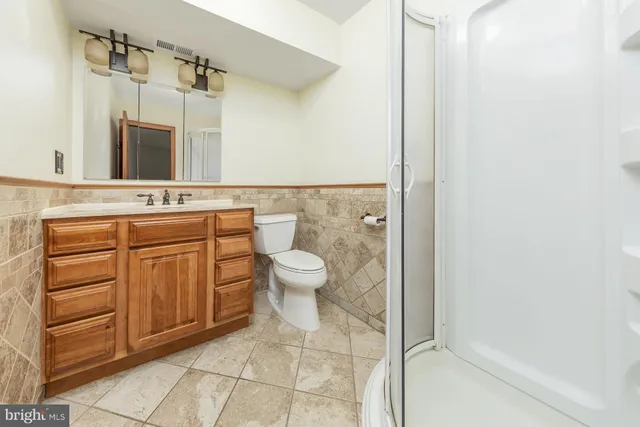 a bathroom with a granite countertop toilet a sink and a mirror