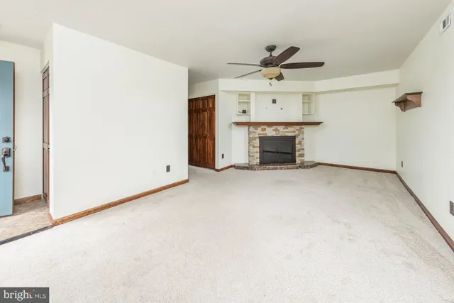 an empty room with fireplace and a ceiling fan