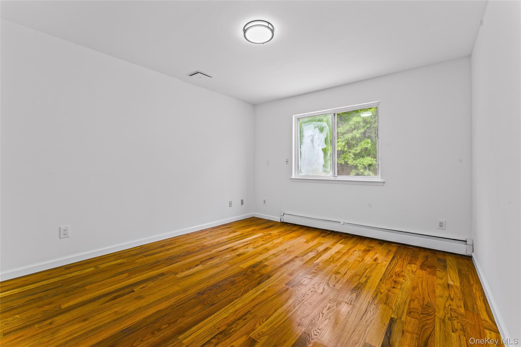 126 Bagatelle Road Melville, NY 11747 - Photo 26 of 50 a view of an empty room with wooden floor and a window