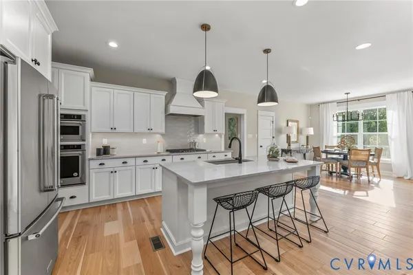 a kitchen with stainless steel appliances granite countertop a stove refrigerator and white cabinets with wooden floor