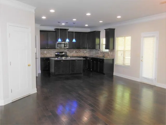 a kitchen with kitchen island granite countertop a stove top oven a sink and a microwave