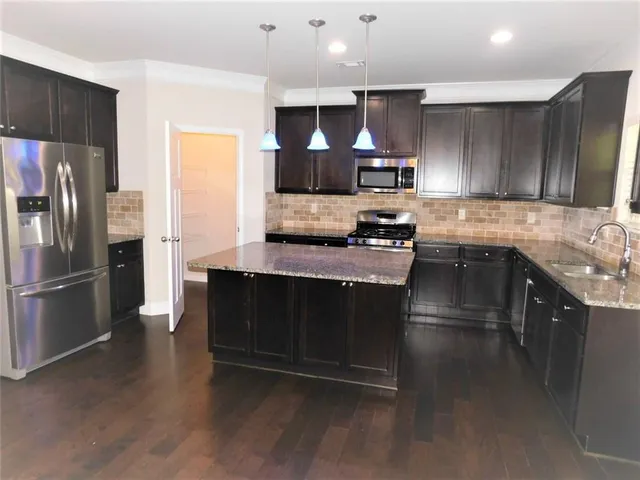 a kitchen with stainless steel appliances granite countertop a stove a sink and a refrigerator