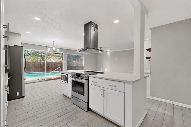 a living room with stainless steel appliances kitchen island granite countertop a sink a counter space and cabinets