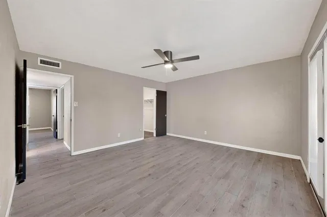 a view of empty room with wooden floor and ceiling fan