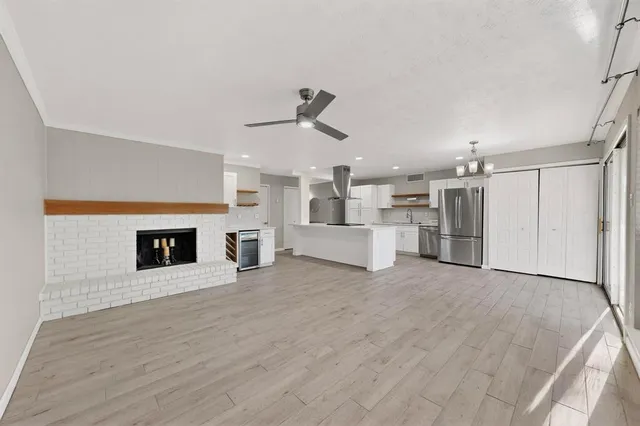 a view of an empty room with wooden floor and a kitchen