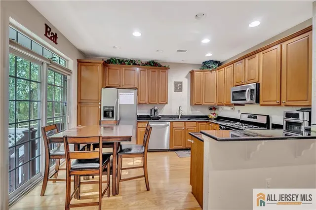 a kitchen with stainless steel appliances granite countertop a stove top oven a sink dishwasher a dining table and chairs with wooden floor