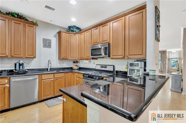 a kitchen with stainless steel appliances granite countertop a stove a sink dishwasher and microwave with wooden cabinets