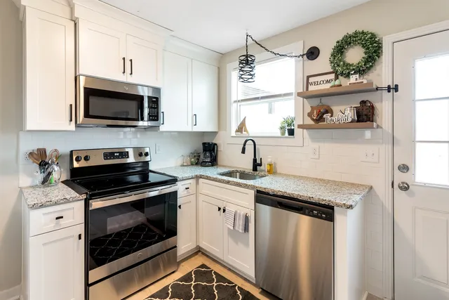 a kitchen with granite countertop white cabinets sink and stainless steel appliances