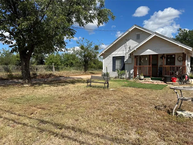 a front view of house with yard and trees in the background