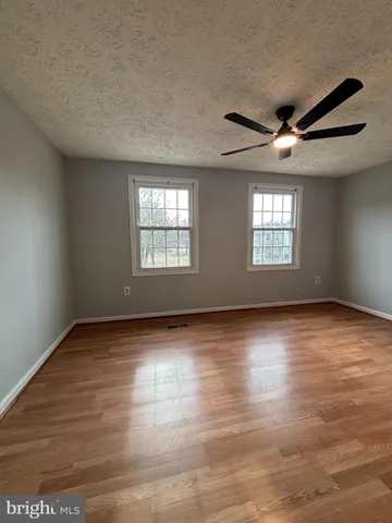 a view of an empty room with wooden floor and windows