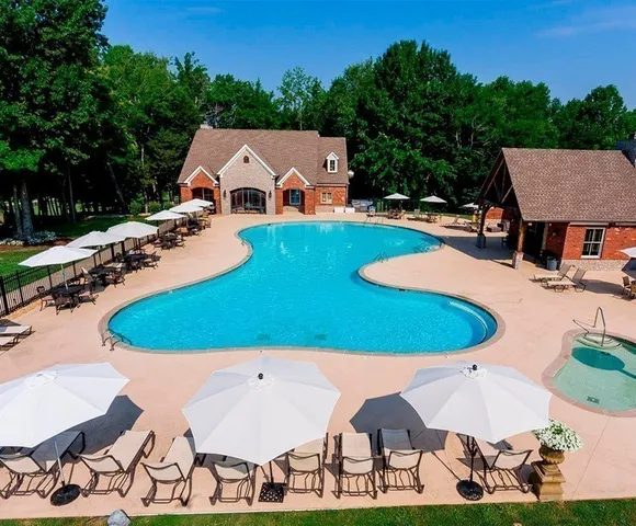 an aerial view of a house with swimming pool and trees