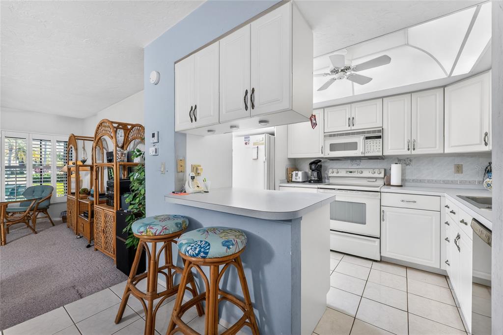 2955 North Beach Road, Unit B614 Englewood, FL 34223 - Photo 18 of 67 a kitchen with stainless steel appliances granite countertop a white cabinets and chairs