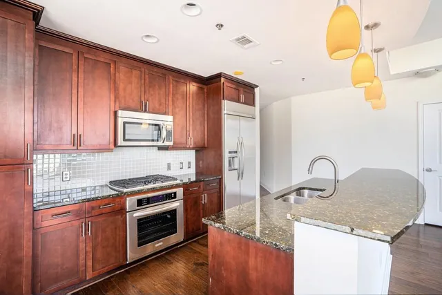 a kitchen with granite countertop a sink stainless steel appliances and cabinets