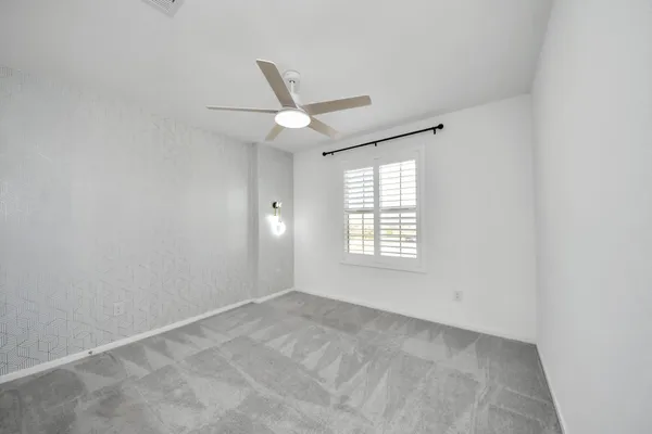 an empty room with a ceiling fan and a window