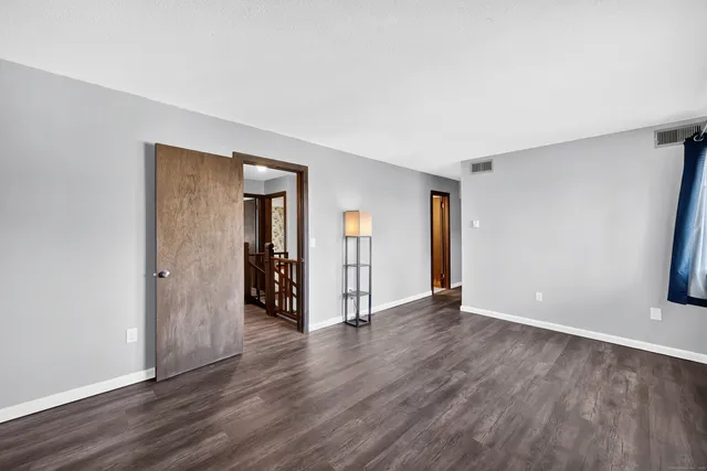 a view of an empty room with wooden floor and closet
