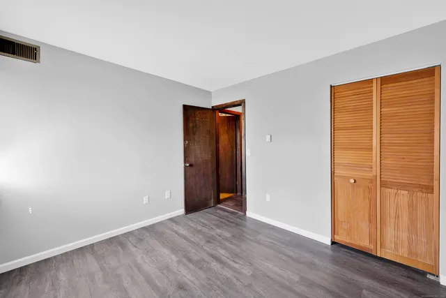 an empty room with wooden floor and closet area
