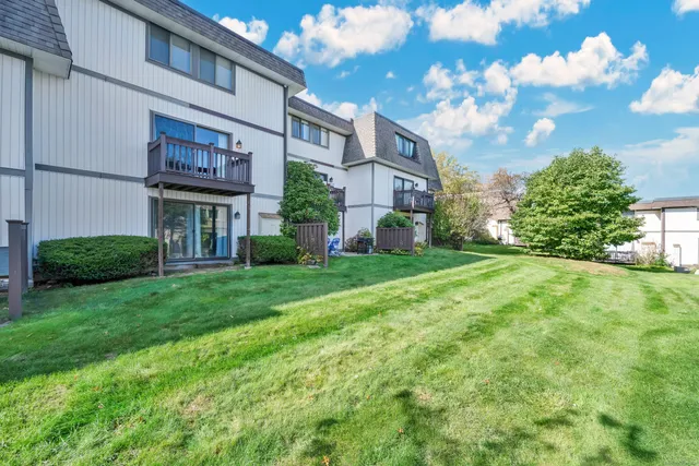 a view of a brick house with a big yard plants and large trees