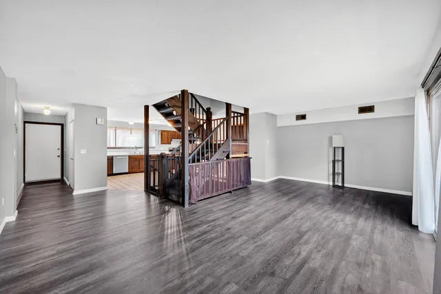a view of an empty room with wooden floor and stairs