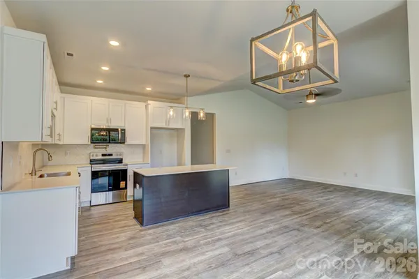 an open kitchen with wooden floor and electronic appliances
