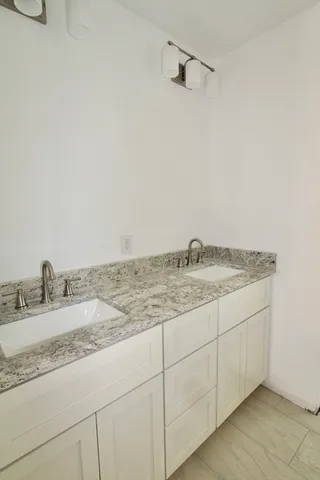 a bathroom with a granite countertop sink and white cabinets