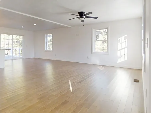 a view of an empty room with a window and wooden floor