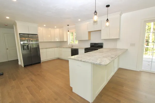 a kitchen with a refrigerator a sink and white cabinets