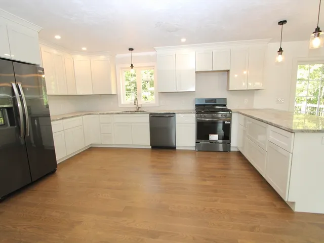 a large kitchen with stainless steel appliances granite countertop a stove a sink dishwasher and a refrigerator